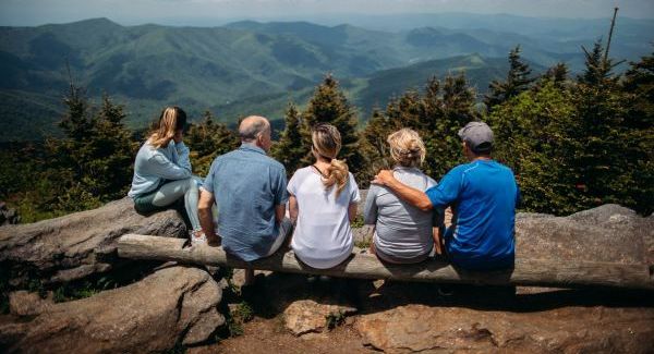 A family sits together looking at a peaceful mountain view