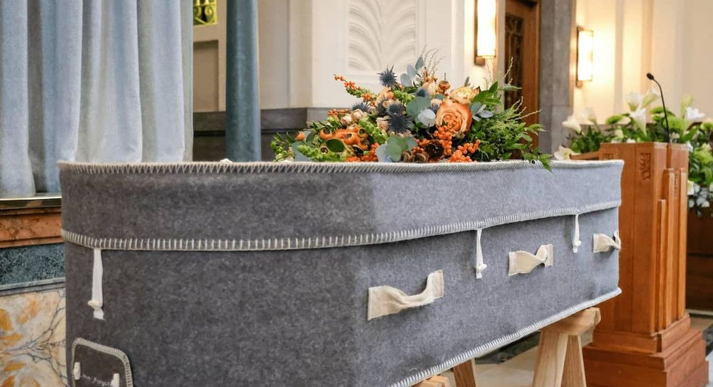 A grey wool coffin with a spray of orange flowers