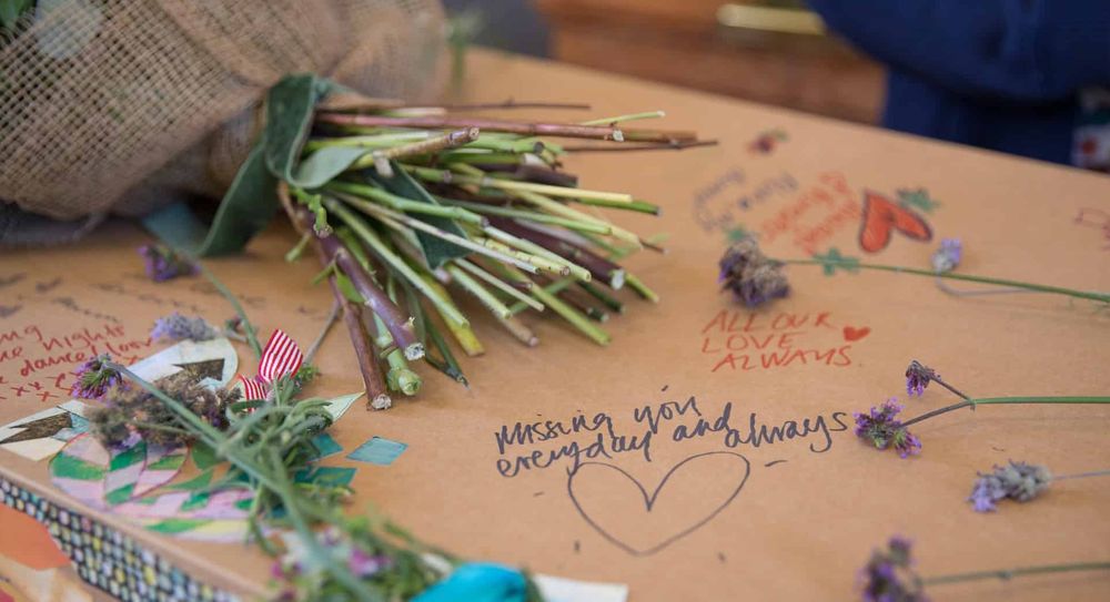 Cardboard coffin with funeral notes and flowers.