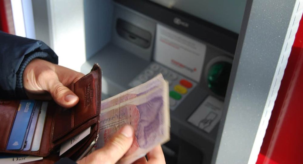 Hands taking money out of a cash point.