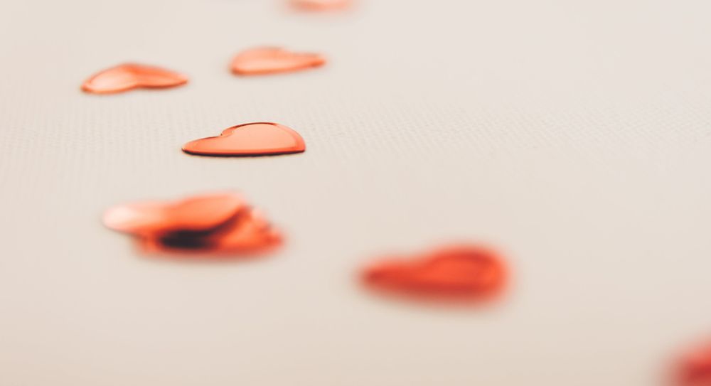 Red heart shaped confetti on a white surface.