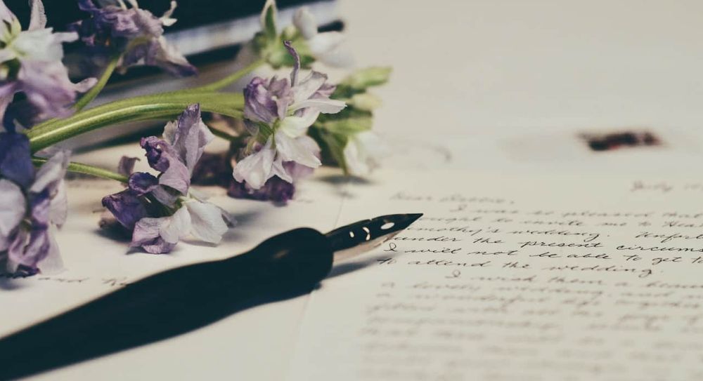 Flowers and a fountain pen lying on a piece of paper.