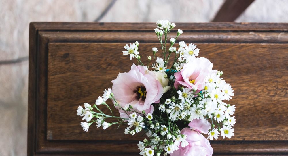 Flowers resting on wooden funeral coffin. 