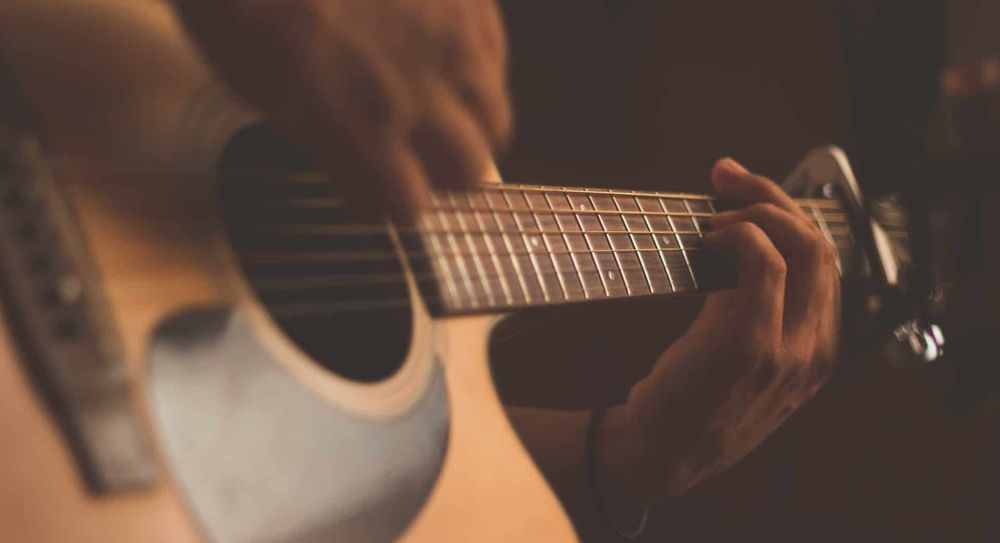 A hand playing an acoustic guitar.
