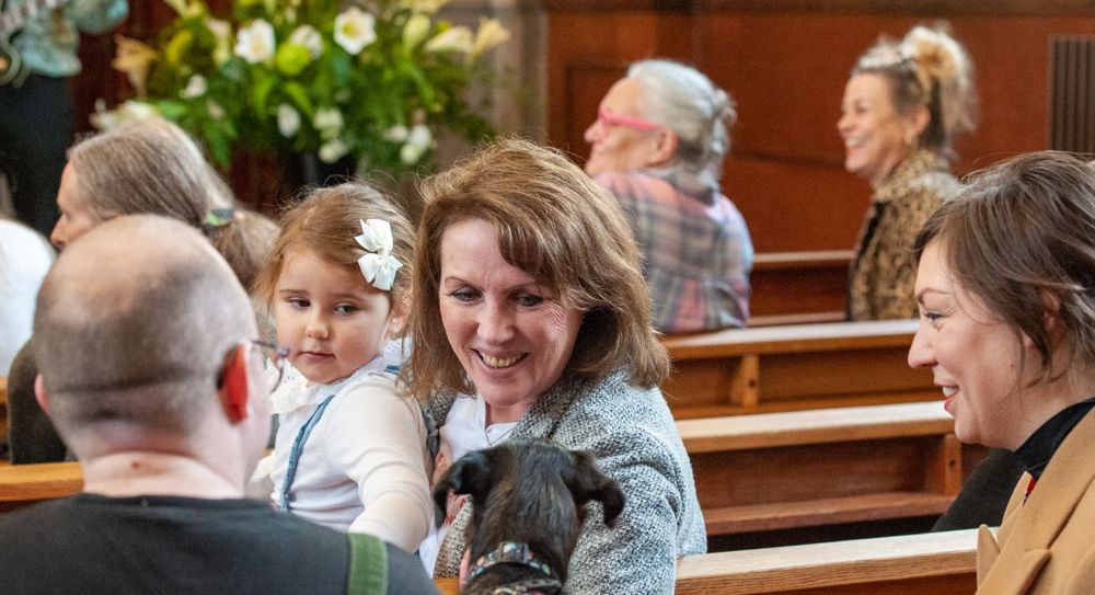 Mother and her young daughter and dog in a church sitting smiling