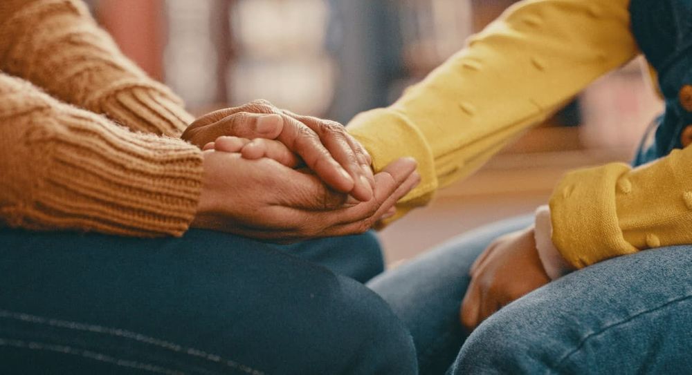 Two people hold hands for support and comfort