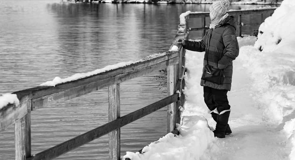 Someone looking out across a lake in the snow.