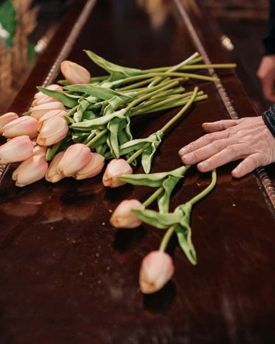  a bunch of flowers laid on a coffin at a simple funeral service.