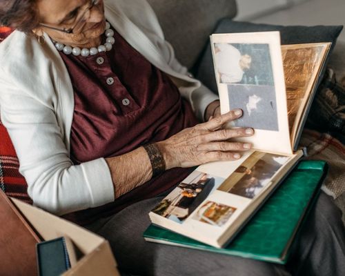 Senior female at home on a sofa looking through an old photo album