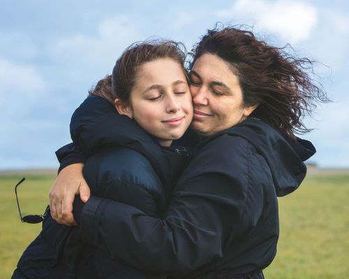 Mother and teenage daughter embracing outdoors