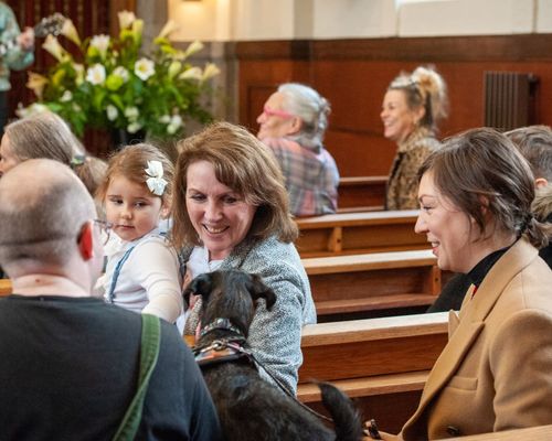 Mother and her young daughter and dog in a church sitting smiling