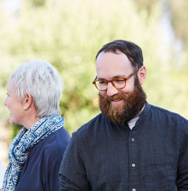 Man with glasses and beard with woman relaxed and smiling at outdoor event