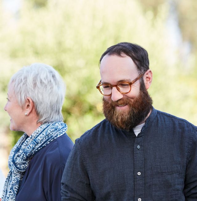 Man with glasses and beard with woman relaxed and smiling at outdoor event