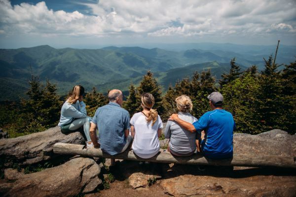 A family sits together looking at a peaceful mountain view