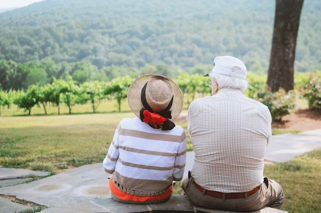 An old couple sit looking at a natural view on a sunny day