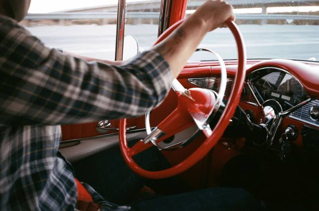 Man driving 1950s car with red interior
