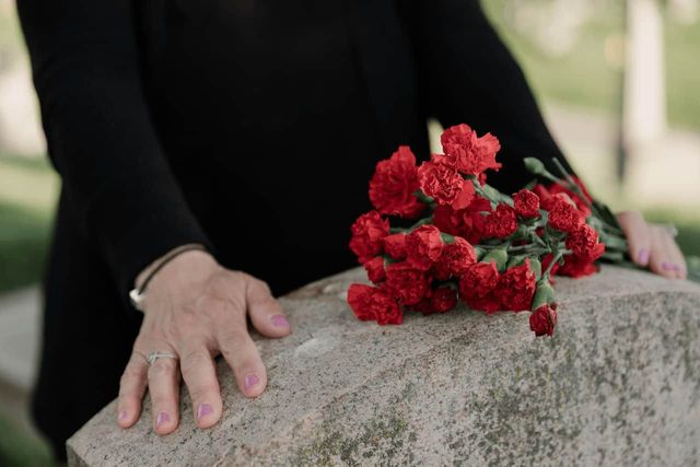 A woman wearing black places flowers on the grave of a loved one