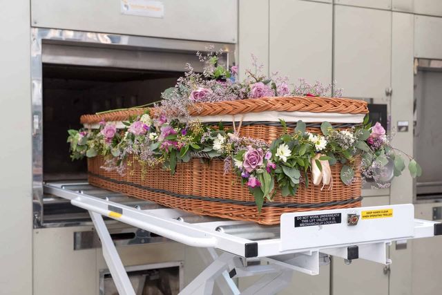A wicker coffin about to be placed inside a cremator.