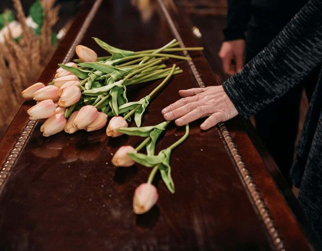  a bunch of flowers laid on a coffin at a simple funeral service.