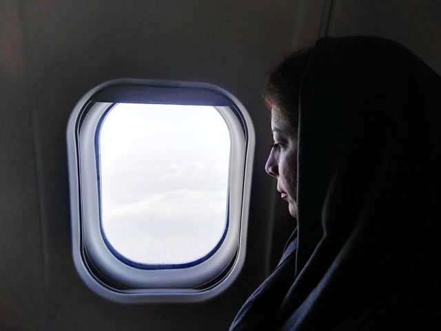 A woman looking out of a plane window.