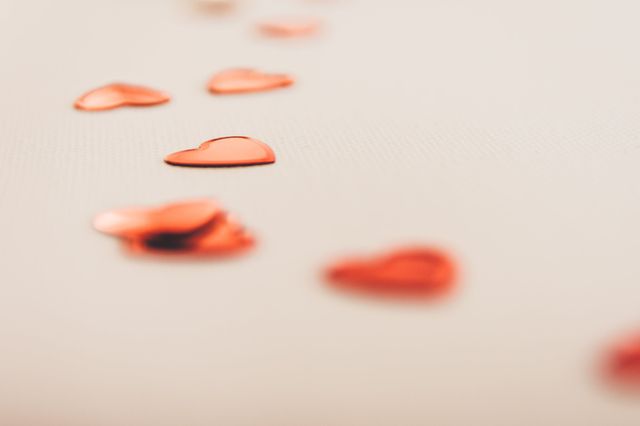 Red heart shaped confetti on a white surface.