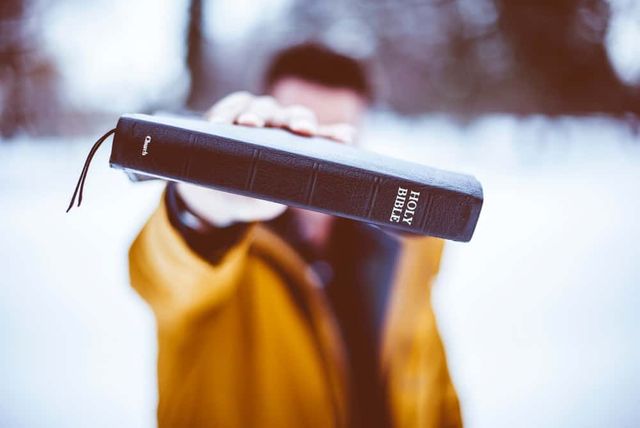 Man holding up a bible on a snowy day. 
