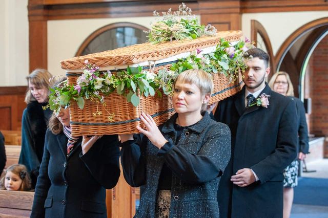 Pallbearers carrying a wicker coffin on their shoulders at a traditional funeral