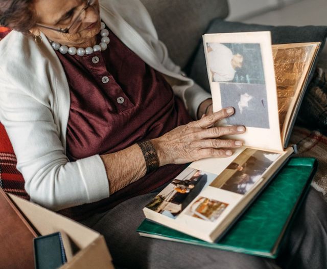 Senior female at home on a sofa looking through an old photo album