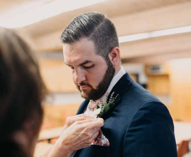 Man in suit getting boutonniere pinned on suit