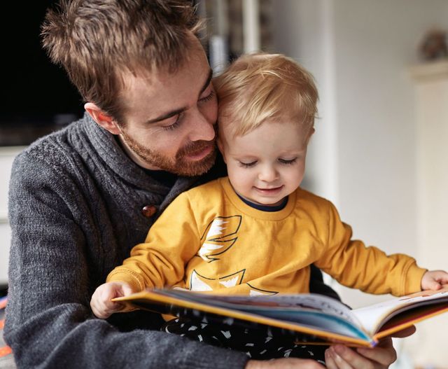 Father with young son on lap reading a book
