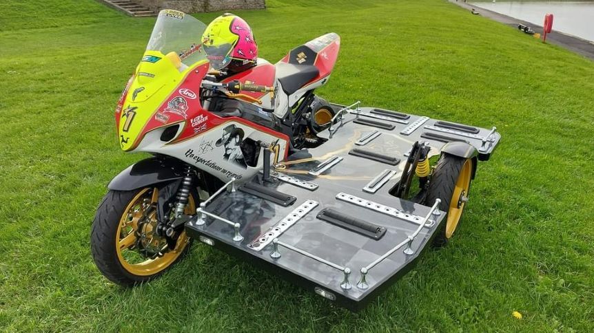 Red, pink and neon yellow superbike hearse - a superbike with a flat sidecar.
