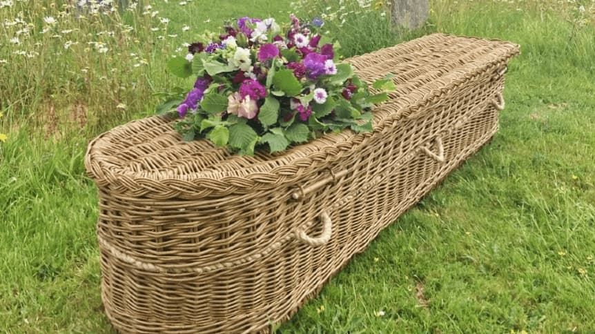 Woven coffin with floral spray on top by Farewell Coffins